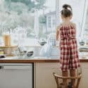Child standing on chair doing dishes