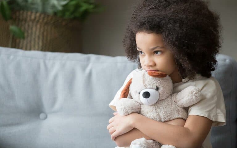 Child holding bear with longing face