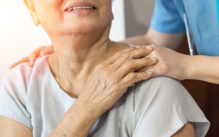 Caregiver holds hand of elderly woman