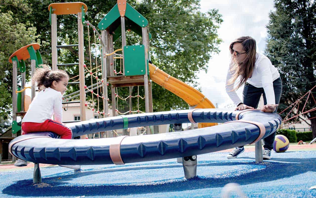 A nanny and child enjoy a day playing on the playground