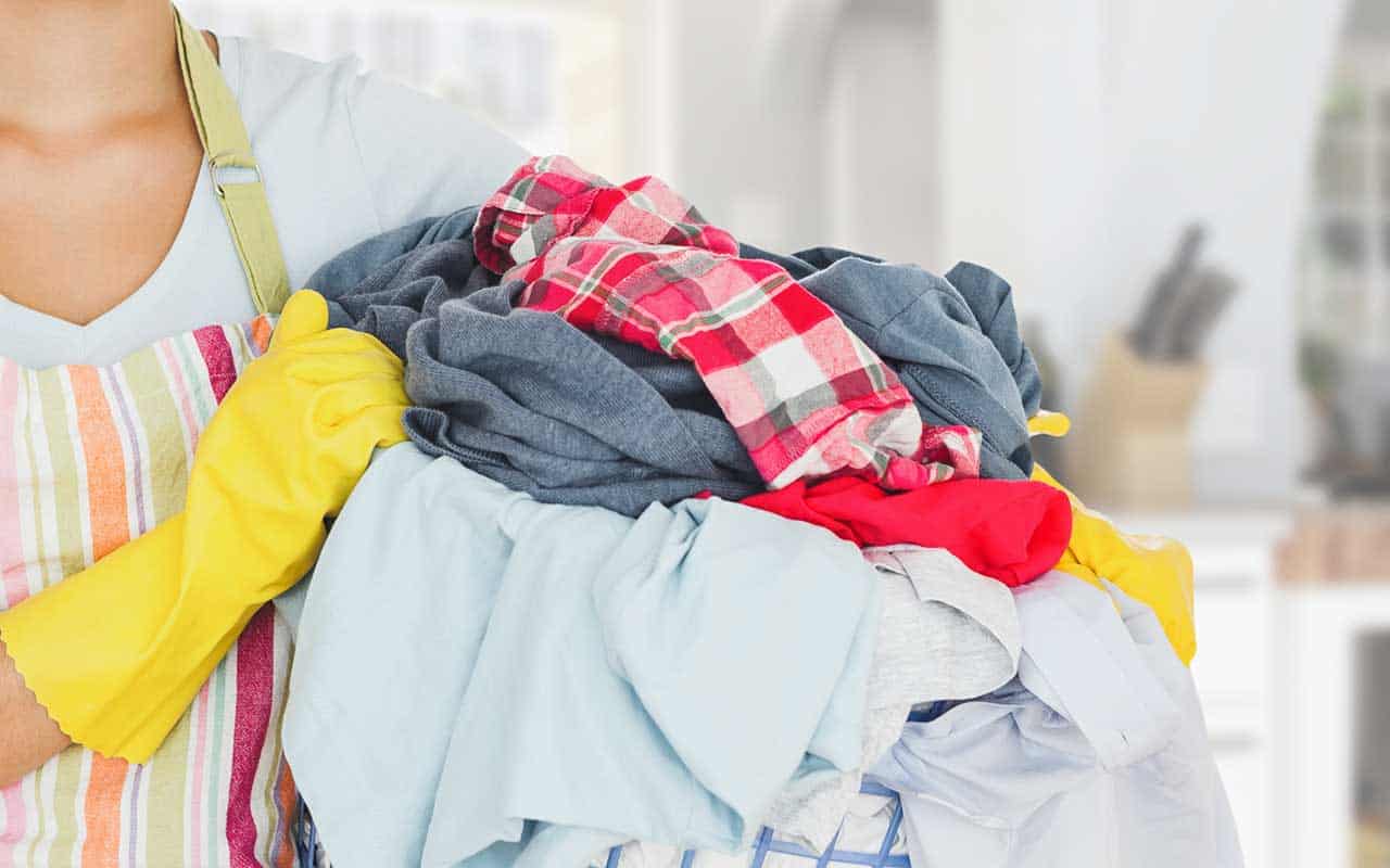 A housekeeper stands with a basket full of laundry