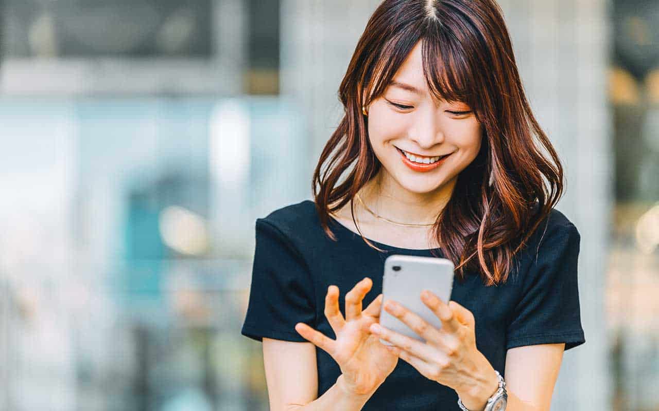 A personal assistant smiles as she confirms appointments on a smart phone