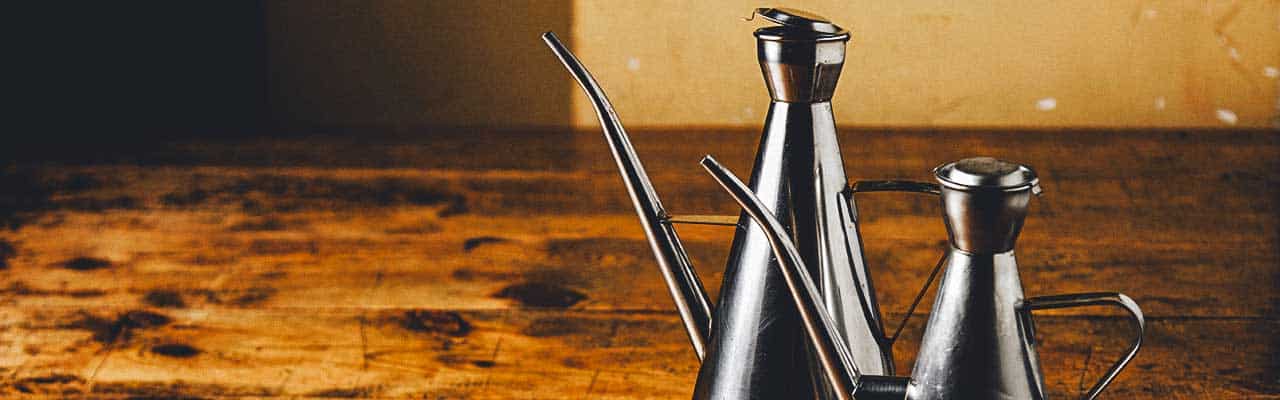 Two stainless steel oil cruets sit on a table