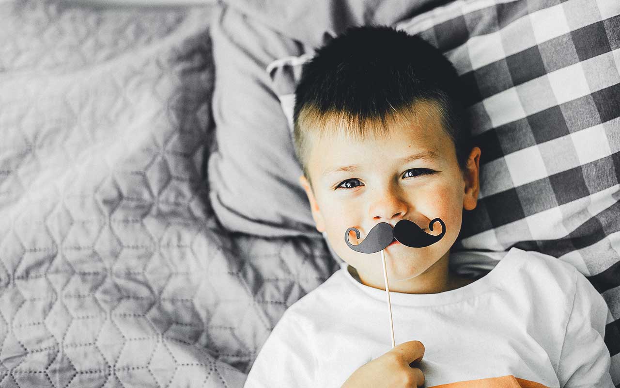 A boy plays with a fake mustache | Household Staffing