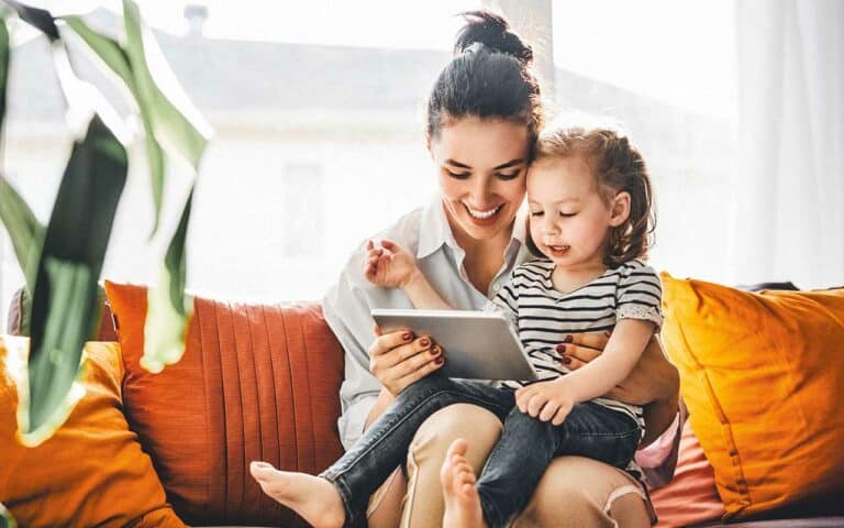 A nanny reads a tablet with a small child | Household Staffing