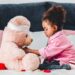 A small girl plays doctor with her pink teddy bear | Household Staffing