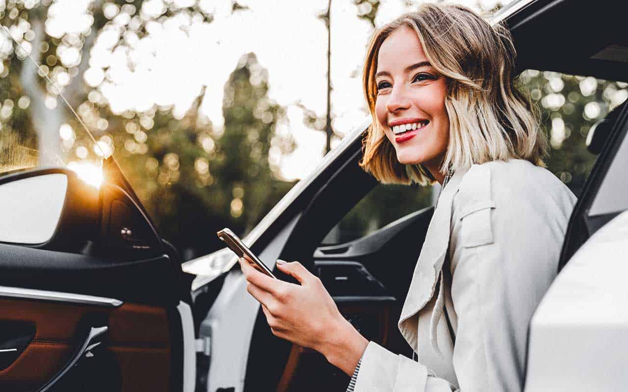 A personal assistant smiles as she leans out of a car | Household Staffing